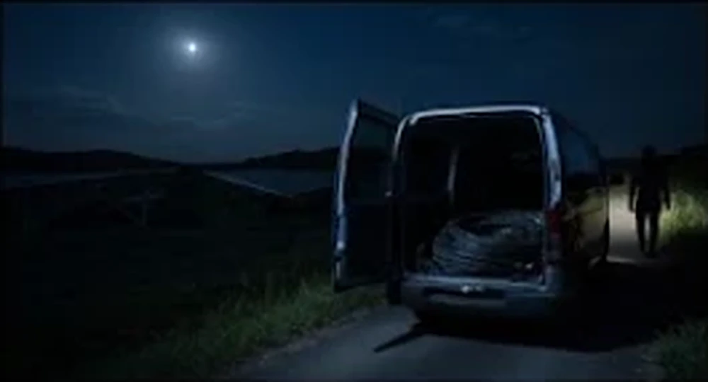 夜の発電所の外に停まったケーブルを積んだ車