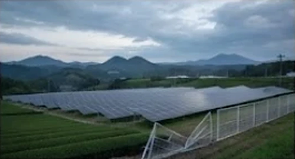 丘陵地の太陽光発電所とめくれたフェンス